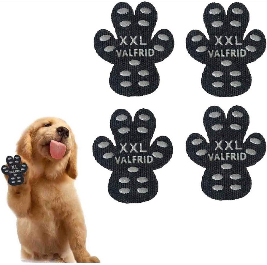 Cuatro almohadillas VALFRID negras con forma de huella y puntos de goma, marcadas con la talla XXL, junto a un golden retriever levantando la pata