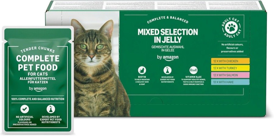 Caja verde y blanca de 48 sobres de comida húmeda para gato en gelatina de la marca by Amazon, junto a un gato atigrado