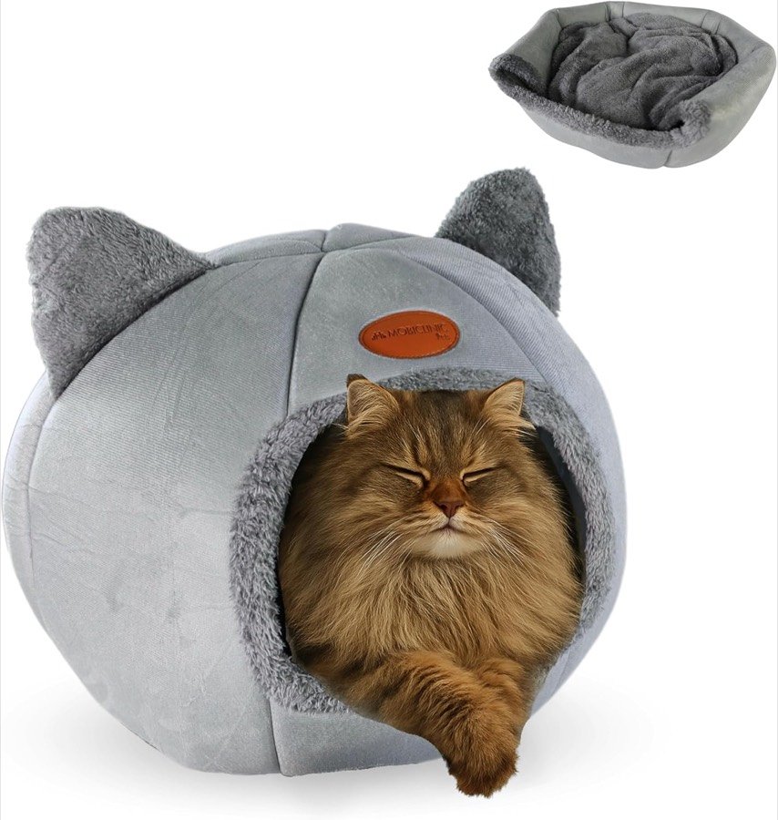 Gato de pelo largo dormido en la entrada de la cama cueva Mobiclinic gris con orejas de gato y el cojín aparte