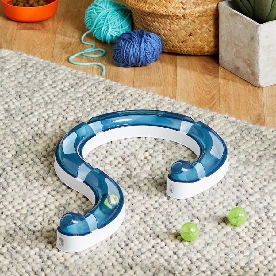 Ver imagen 2 de 3: El circuito Catit Play Circuit montado en forma de espiral sobre una alfombra, con dos bolas verdes al lado