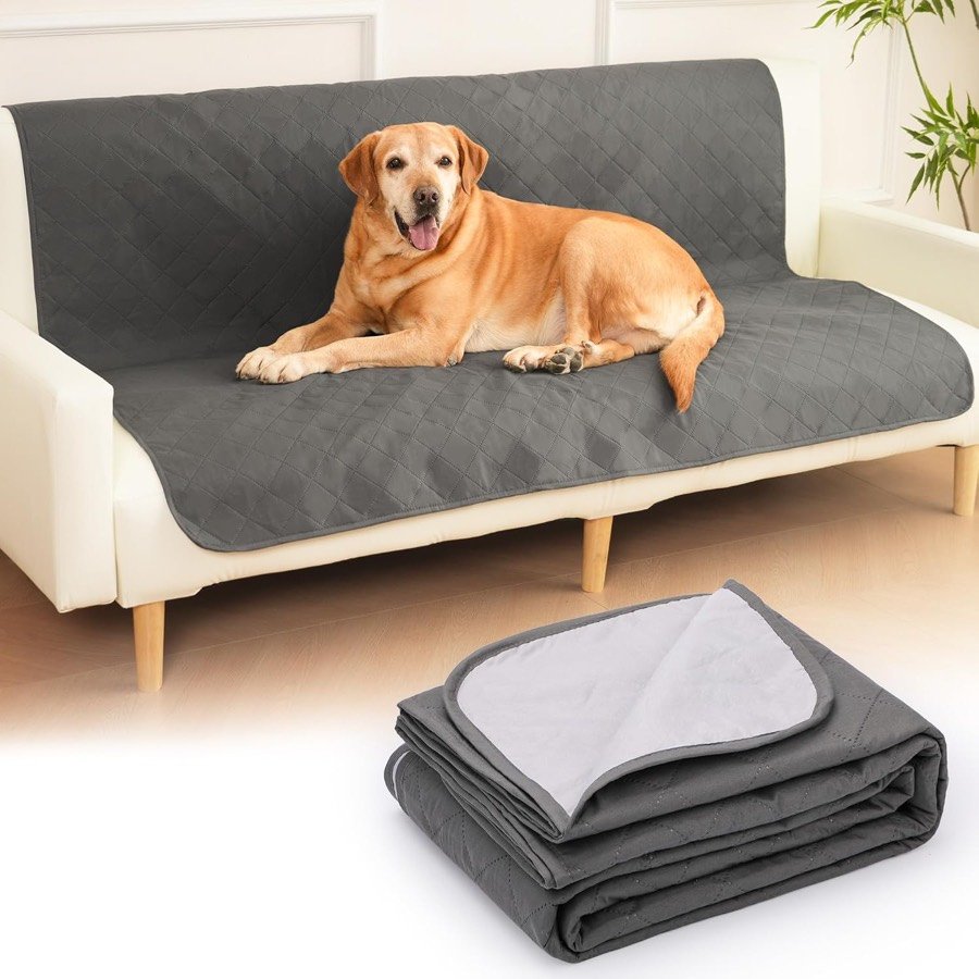 Labrador tumbado sobre la manta HezzLuv gris oscuro echada en un sofá blanco, con la manta doblada mostrando la cara gris claro