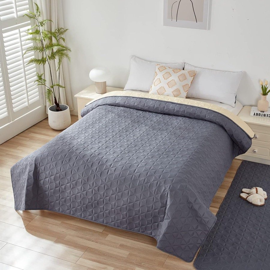 Ver imagen 2 de 6: La manta Taiyang gris cubriendo una cama de matrimonio, con el reverso beige asomando