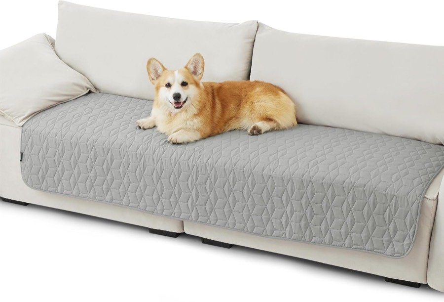 Corgi tumbado sobre el protector Bedsure gris acolchado que cubre los asientos de un sofá blanco